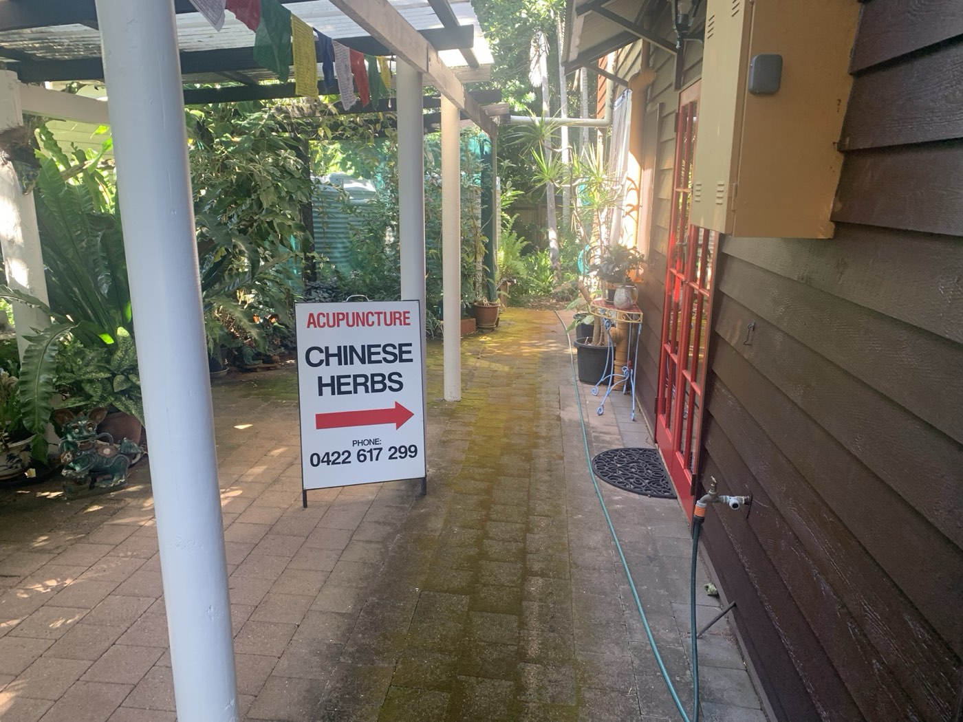 Acupuncture and Chinese herbs sign pointing along the garden path to the clinic entrance