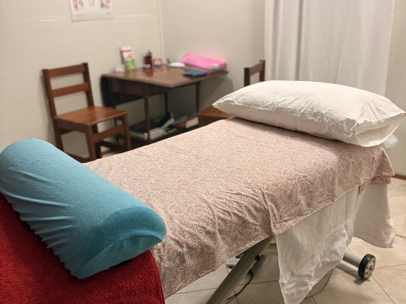 Treatment table made up with fresh linen, acupuncture point chart on the wall behind